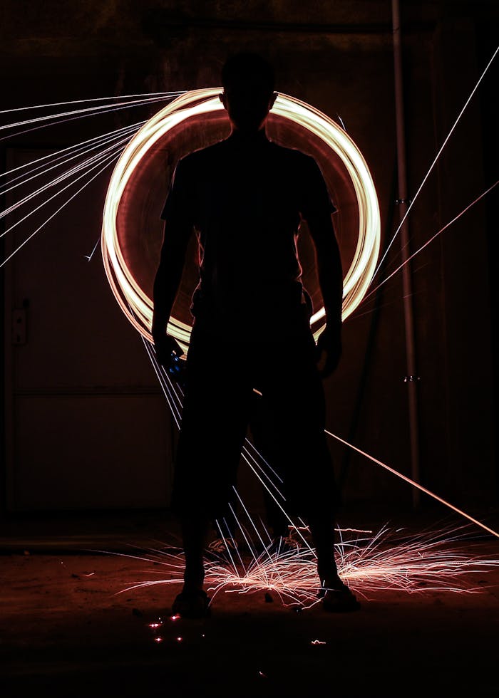 Silhouette of a performer creating mesmerizing fire dance with light trails in the night.