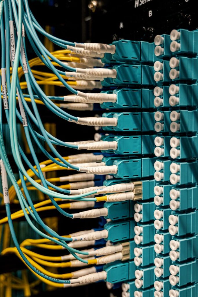 pexels photo 4497197 Blue and yellow optical fiber cables connected to ports in a server room.